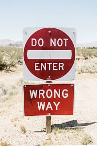 The Dangers of DIY AI Estate Planning: Why Professional Legal Review is Essential A metal road sign in a desert landscape with a 'DO NOT ENTER' sign on top and a 'WRONG WAY' sign below it.